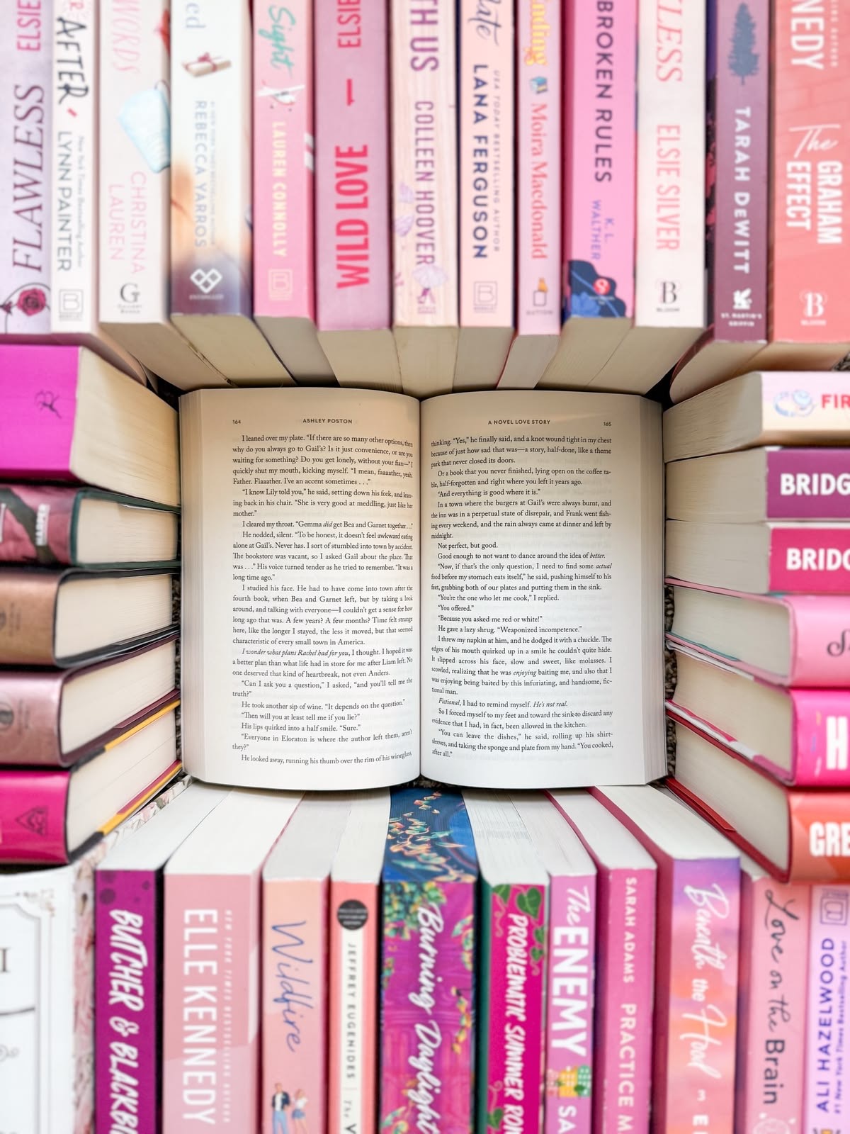 An open book nestled in a fortress of pink romance novels